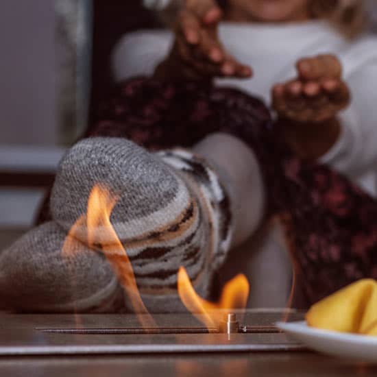 Une femme manifeste sa joie derrière la flamme d'une cheminée de table au bioéthanol